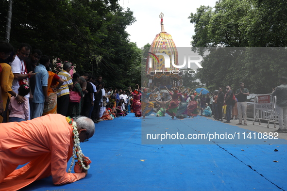 A Hindu devotee is offering prayer as artists are performing on the last day of the week-long celebration of Rath Yatra, or chariot processi...