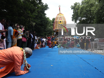 A Hindu devotee is offering prayer as artists are performing on the last day of the week-long celebration of Rath Yatra, or chariot processi...