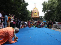 A Hindu devotee is offering prayer as artists are performing on the last day of the week-long celebration of Rath Yatra, or chariot processi...