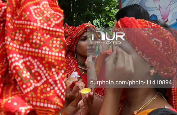 An artist is getting her make-up done before she performs on the last day of the week-long celebration of Rath Yatra, or chariot procession,...