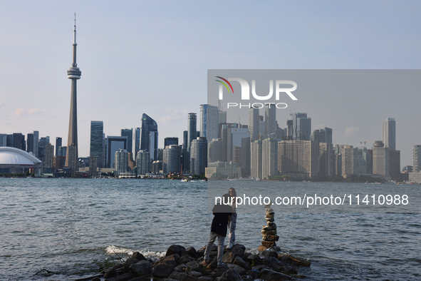 A woman is posing for a photo by the skyline of the city of Toronto seen from Centre Island in Toronto, Ontario, Canada, on July 13, 2024. 