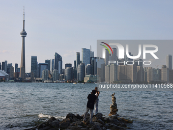 A woman is posing for a photo by the skyline of the city of Toronto seen from Centre Island in Toronto, Ontario, Canada, on July 13, 2024. (