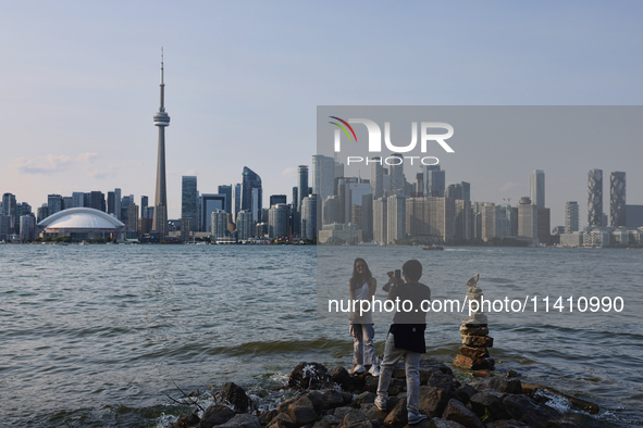 A woman is posing for a photo by the skyline of the city of Toronto seen from Centre Island in Toronto, Ontario, Canada, on July 13, 2024. 