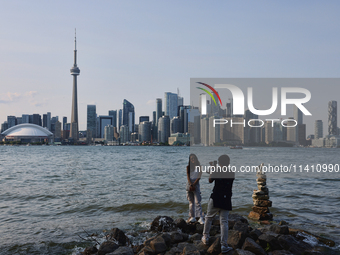 A woman is posing for a photo by the skyline of the city of Toronto seen from Centre Island in Toronto, Ontario, Canada, on July 13, 2024. (