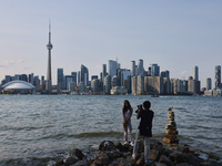 A woman is posing for a photo by the skyline of the city of Toronto seen from Centre Island in Toronto, Ontario, Canada, on July 13, 2024. (