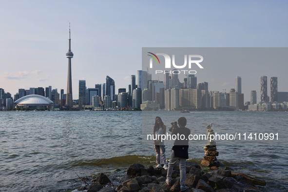 A woman is posing for a photo by the skyline of the city of Toronto seen from Centre Island in Toronto, Ontario, Canada, on July 13, 2024. 