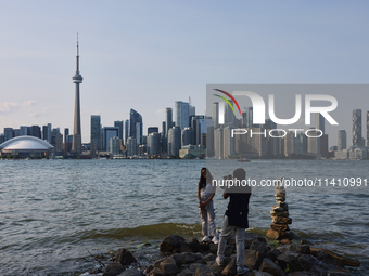 A woman is posing for a photo by the skyline of the city of Toronto seen from Centre Island in Toronto, Ontario, Canada, on July 13, 2024. (