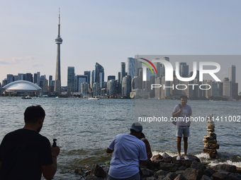 A man is posing for a photo by the skyline of the city of Toronto seen from Centre Island in Toronto, Ontario, Canada, on July 13, 2024. (