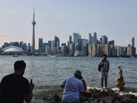 A man is posing for a photo by the skyline of the city of Toronto seen from Centre Island in Toronto, Ontario, Canada, on July 13, 2024. (