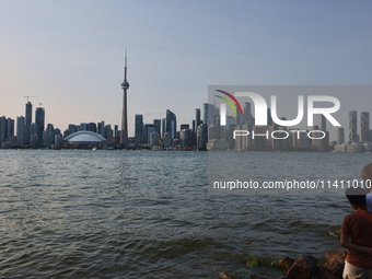 People are standing by the skyline of the city of Toronto, seen from Centre Island in Toronto, Ontario, Canada, on July 13, 2024. (