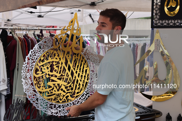 A vendor is showing off handmade Islamic calligraphy items during the Taste of the Middle East Food Festival in Toronto, Ontario, Canada, on...