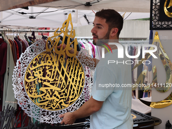 A vendor is showing off handmade Islamic calligraphy items during the Taste of the Middle East Food Festival in Toronto, Ontario, Canada, on...