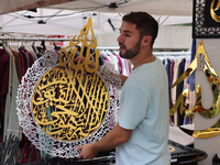 A vendor is showing off handmade Islamic calligraphy items during the Taste of the Middle East Food Festival in Toronto, Ontario, Canada, on...