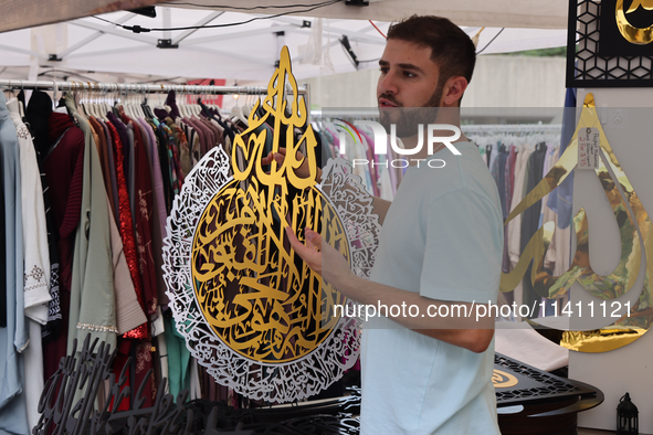 A vendor is showing off handmade Islamic calligraphy items during the Taste of the Middle East Food Festival in Toronto, Ontario, Canada, on...