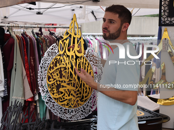 A vendor is showing off handmade Islamic calligraphy items during the Taste of the Middle East Food Festival in Toronto, Ontario, Canada, on...