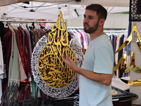 A vendor is showing off handmade Islamic calligraphy items during the Taste of the Middle East Food Festival in Toronto, Ontario, Canada, on...