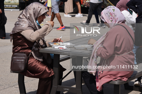 Women are enjoying various Middle Eastern foods during the Taste of the Middle East Food Festival in Toronto, Ontario, Canada, on July 06, 2...