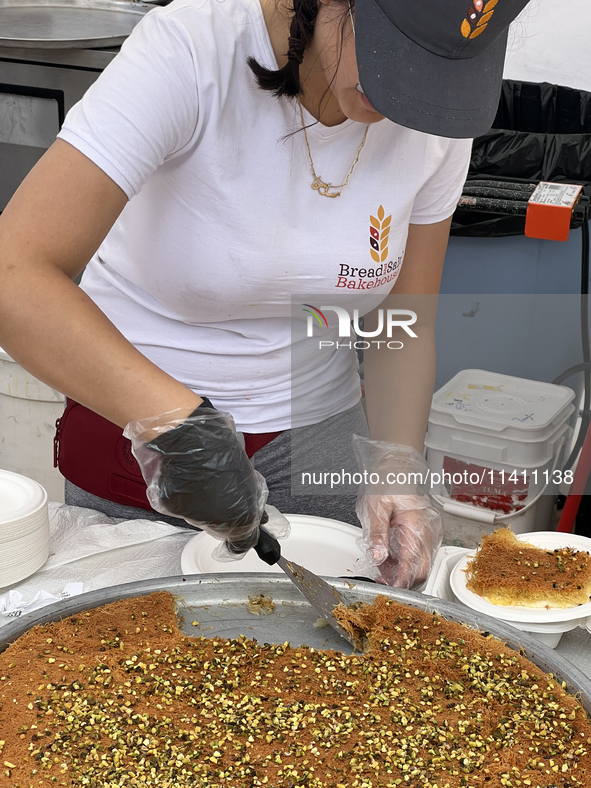 A woman is serving Kunafa in Toronto, Ontario, Canada, on June 06, 2024. Kunafa (knafeh) is a traditional Arabic dessert, made with spun pas...