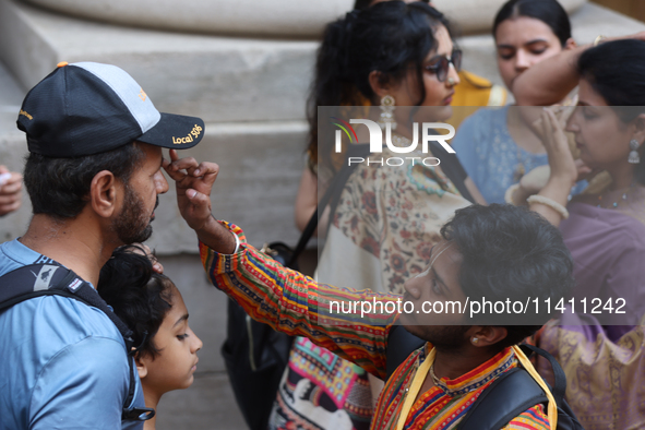 Tikkas are being applied to the foreheads of devotees as thousands of Hindu devotees are taking part in the procession during the annual Rat...