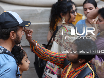 Tikkas are being applied to the foreheads of devotees as thousands of Hindu devotees are taking part in the procession during the annual Rat...