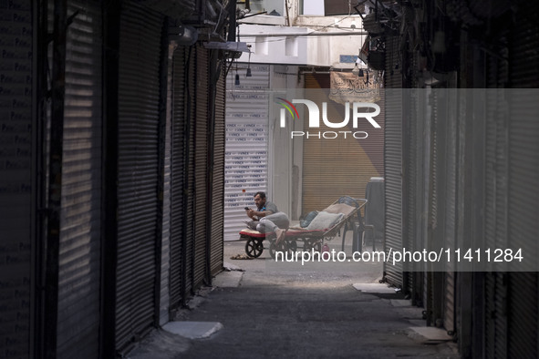 An Iranian worker is using his cellphone while sitting on his cart at a closed bazaar during a religious festival to commemorate Tasoua, a d...