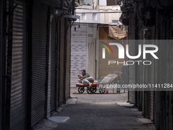 An Iranian worker is using his cellphone while sitting on his cart at a closed bazaar during a religious festival to commemorate Tasoua, a d...