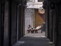 An Iranian worker is using his cellphone while sitting on his cart at a closed bazaar during a religious festival to commemorate Tasoua, a d...