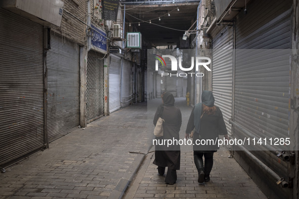 Two Iranian women are walking along a closed bazaar during a religious festival to commemorate Tasoua, a day ahead of Ashura, in the Grand B...