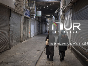 Two Iranian women are walking along a closed bazaar during a religious festival to commemorate Tasoua, a day ahead of Ashura, in the Grand B...