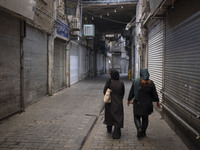 Two Iranian women are walking along a closed bazaar during a religious festival to commemorate Tasoua, a day ahead of Ashura, in the Grand B...