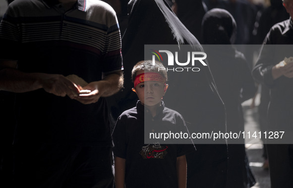 A young Iranian boy is wearing a religious headband while posing for a photograph during a religious festival to commemorate Tasoua, a day a...