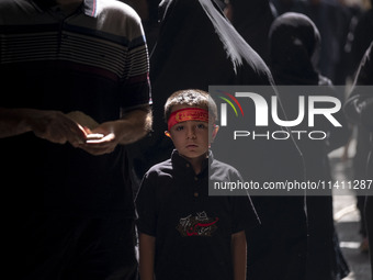 A young Iranian boy is wearing a religious headband while posing for a photograph during a religious festival to commemorate Tasoua, a day a...