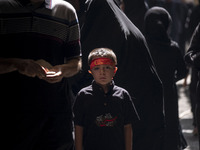 A young Iranian boy is wearing a religious headband while posing for a photograph during a religious festival to commemorate Tasoua, a day a...