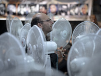 An Iranian man is praying while standing between fans that are cooling a mosque, during a religious festival to commemorate Tasoua, a day ah...