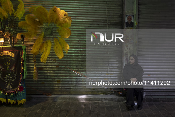 An Iranian woman is sitting next to a religious symbol while participating in a religious festival to commemorate Tasoua, a day ahead of Ash...