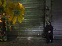 An Iranian woman is sitting next to a religious symbol while participating in a religious festival to commemorate Tasoua, a day ahead of Ash...