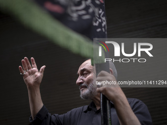 An elderly Iranian man is beating himself while holding a religious flag during a religious festival to commemorate Tasoua, a day ahead of A...