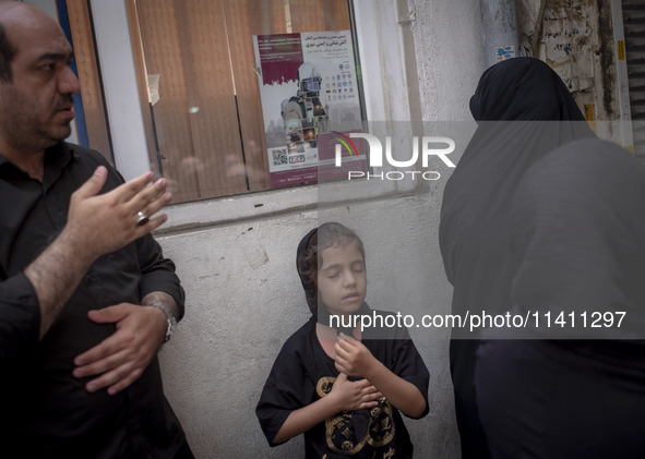 A young Iranian girl and a man are beating themselves while participating in a religious festival to commemorate Tasoua, a day ahead of Ashu...