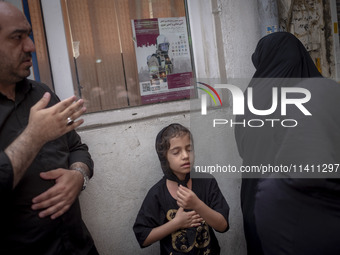 A young Iranian girl and a man are beating themselves while participating in a religious festival to commemorate Tasoua, a day ahead of Ashu...