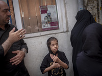 A young Iranian girl and a man are beating themselves while participating in a religious festival to commemorate Tasoua, a day ahead of Ashu...