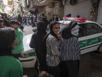 A young Iranian woman is smiling while standing next to a police vehicle with her relatives, during a religious festival to commemorate Taso...