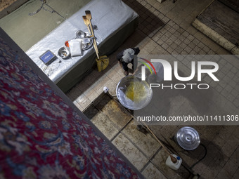 An Iranian man is loading oil into a large pot to bake donated meals during a religious festival to commemorate Tasoua, a day ahead of Ashur...