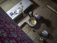 An Iranian man is loading oil into a large pot to bake donated meals during a religious festival to commemorate Tasoua, a day ahead of Ashur...