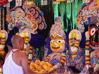 A Hindu priest is placing offerings by the idols of Goddesses Subhadra, Balabhadra, and Lord Jagannath during the annual Rath Yatra festival...