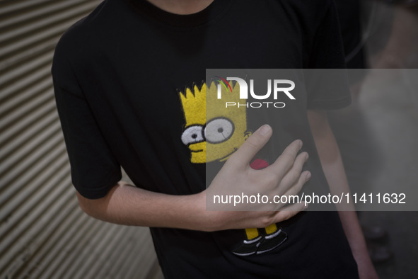 A young Iranian boy is beating himself while wearing a T-shirt featuring an image of Bart Simpson, while participating in a religious festiv...