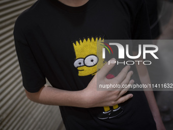 A young Iranian boy is beating himself while wearing a T-shirt featuring an image of Bart Simpson, while participating in a religious festiv...