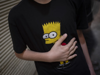 A young Iranian boy is beating himself while wearing a T-shirt featuring an image of Bart Simpson, while participating in a religious festiv...