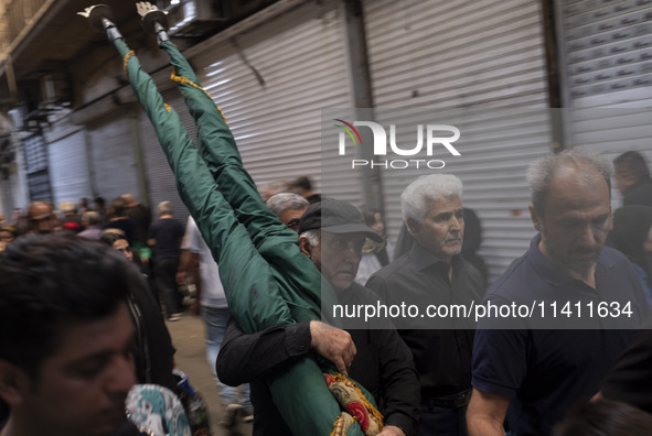 An Iranian man is carrying a religious flag while walking along a bazaar during a religious festival to commemorate Tasoua, a day ahead of A...