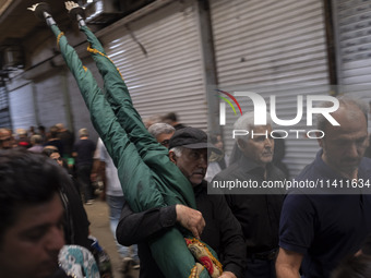 An Iranian man is carrying a religious flag while walking along a bazaar during a religious festival to commemorate Tasoua, a day ahead of A...