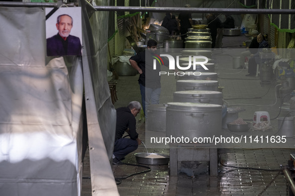 An Iranian man is standing next to the large pots while preparing donated meals during a religious festival to commemorate Tasoua, a day ahe...